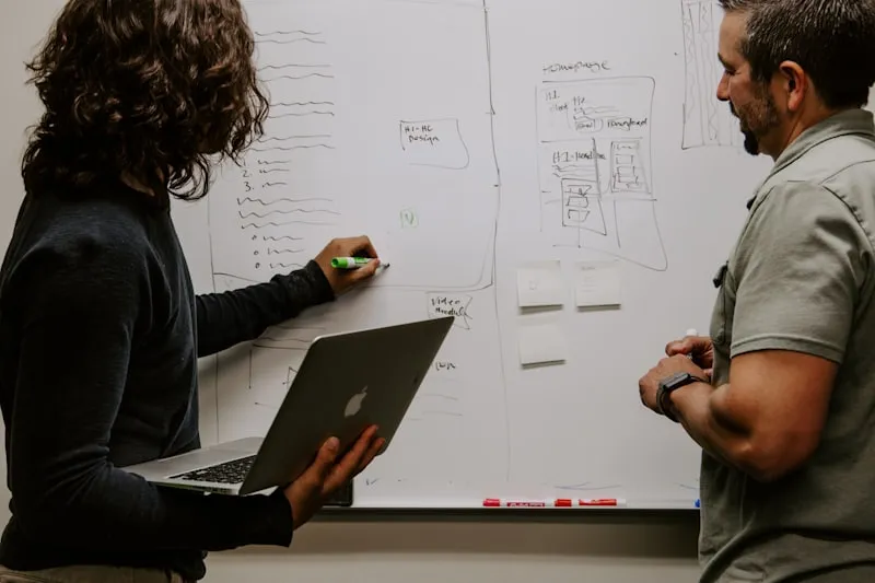 Two colleagues collaborating on a project plan at a whiteboard
